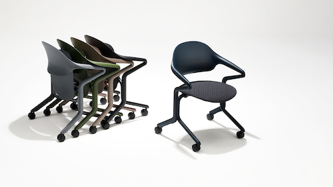 Een groep van vier Fuld Nesting Chairs in verschillende kleuren en afwerkingen naast een enkele Fuld Nesting Chair in Nightfall met een gebreide zitting.