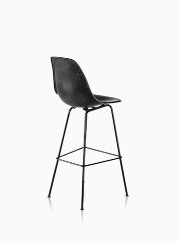 Three-quarter rear view of a black Eames Molded Fiberglass Stool.