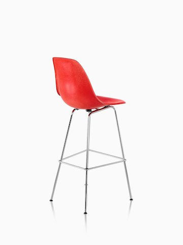 Three-quarter rear view of a red Eames Molded Fiberglass Stool. 