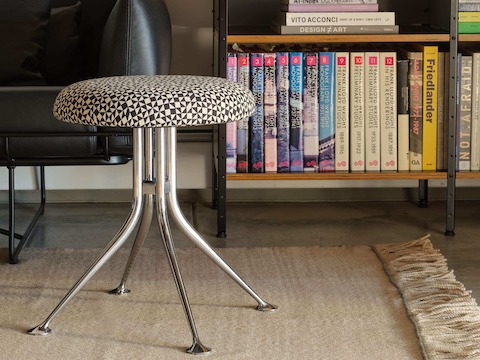 A single Girard stool in a living room with an aluminium base and upholstered in Checker Split by Alexander Girard.