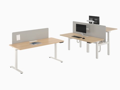 A freestanding Nevi Sit-to-Stand Desk next to a back-to-back two-desk configuration.