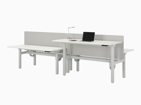 A four-desk configuration of Nevi Sit-to-Stand Desks in white with grey fabric screens. Front right desk raised to standing height.