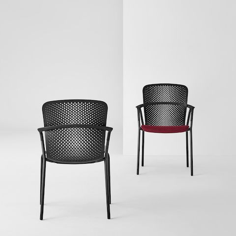 Two black Keyn side chairs facing each other; one has a crimson seat and the other has a black seat.