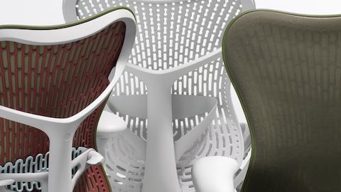 Close-up of the backs of three Mirra 2 Chairs. One is a colour-block olive chair, one is an olive chair with a Butterfly back and the other is an alpine chair with a TriFlex back.