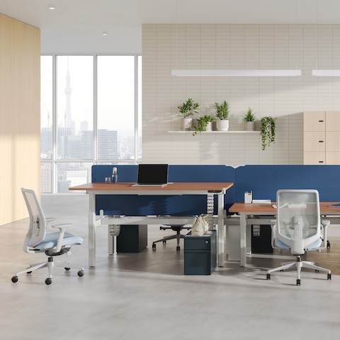 A six-desk configuration of Nevi Sit-to-Stand Desks with blue fabric screens, and Trac pedestals in Nightfall with metal drawer pulls.