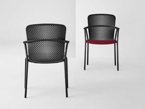 Two black Keyn side chairs facing each other. One chair has a crimson seat and the other a black seat.