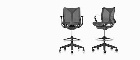 Two low-back Cosm Stools in Graphite dark grey, one viewed from the back, one viewed from an angle.