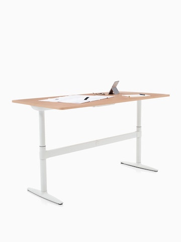 An Atlas Office Landscape desk positioned at standing height, with papers and a tablet on top. Select to go to the Atlas Office Landscape product page.