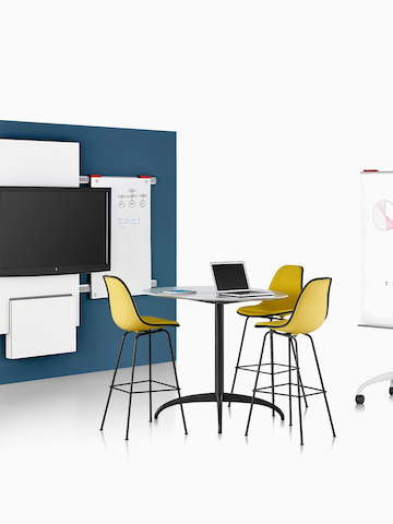 A study area featuring Exclave collaboration elements and Eames Moulded Plastic Stools. Select to go to the Exclave product page.