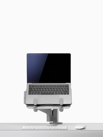 An open laptop raised from a desk and supported by a grey Lima Laptop Mount and Lima Monitor Arm.