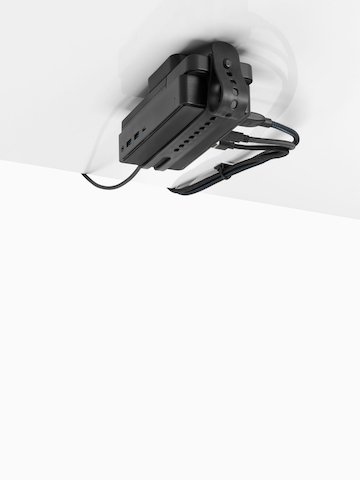 Loop Micro Mount attached under a desk cradling a thin client or power docking station with attached cables that are routed tidily to the edge and above the desk. Select to go to the Loop Micro Mount product page.