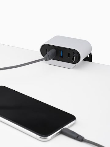 Close-up of Ondo Work Surface Mount on a desk with power cable connected. Select to go to the Ondo Connectivity Module product page.