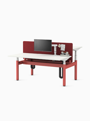 Back-to-back Ratio height-adjustable desks positioned at seating and standing heights, with back-to-back shared privacy screen and a high capacity tray on a white sweep.