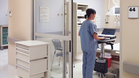 A nurse uses a Mobile Technology Cart in a patient room.
